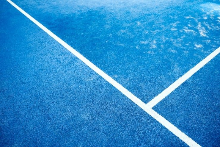 Líneas blancas sobre el césped sintético azul de una cancha de pádel